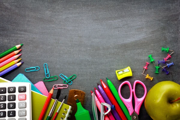 depositphotos_48858583-stock-photo-school-supplies-on-blackboard-background.webp